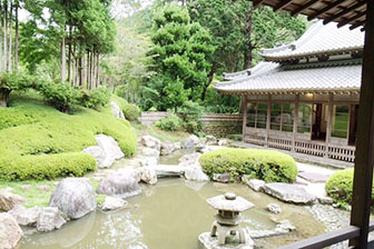 灯篭と小さな池、日本家屋と緑が美しい庭園の写真