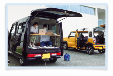 舞阪協働センター駐車場にて車両の中で作業をする学生写真