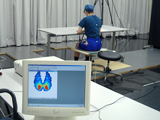 椅子に座った姿勢や動きの測定のためにセンサーをつけている被験者の画像