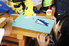 子どもが学生スタッフと材料を貼りながら絵本を制作する様子