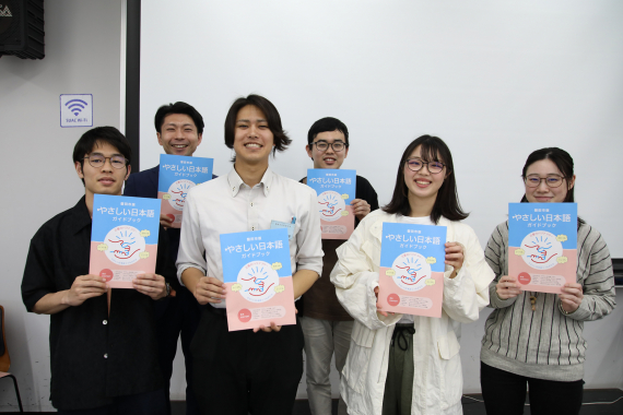 ガイドブックを手に集合写真に写る学生たち