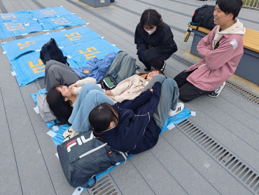 ブルーシートの上に横になり広さを確かめる学生たち