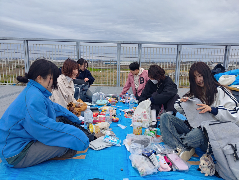ブルーシートの上で防災グッズを広げる学生たち