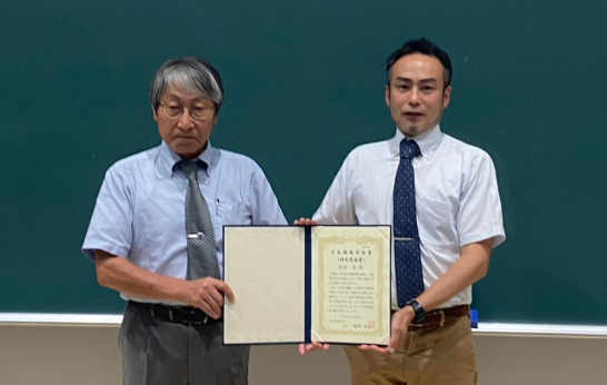 日本環境学会賞(研究奨励賞)の表彰状を受け取った武田准教授の画像