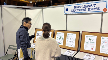 大学サミットにて来場者に説明する学生の写真