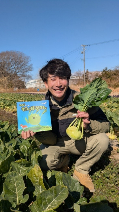 絵本『ラビくんのだいぼうけん』とコールラビを持つ農園アグレスノーバの花積義人代表