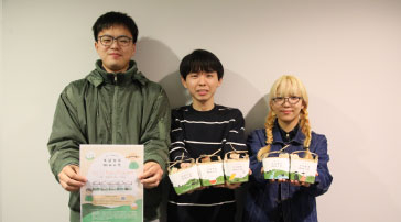 収穫したお米と販売のチラシを手にした引佐耕作隊の集合写真