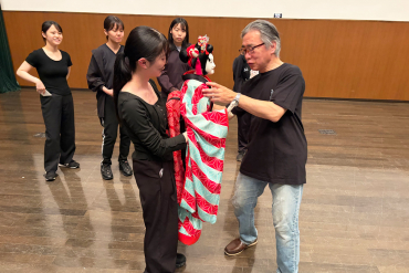 豊松清十郎さんから人形の扱い方の指導を受ける学生の画像