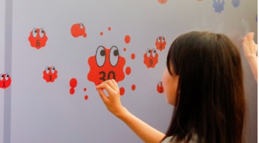 ディスプレイに表示される赤いスライムを操作する子どもの様子の画像